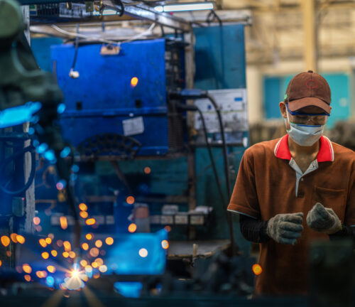 Asian worker working in old chinese factory in robot auto welding machine section and welding for assembly matal part, China